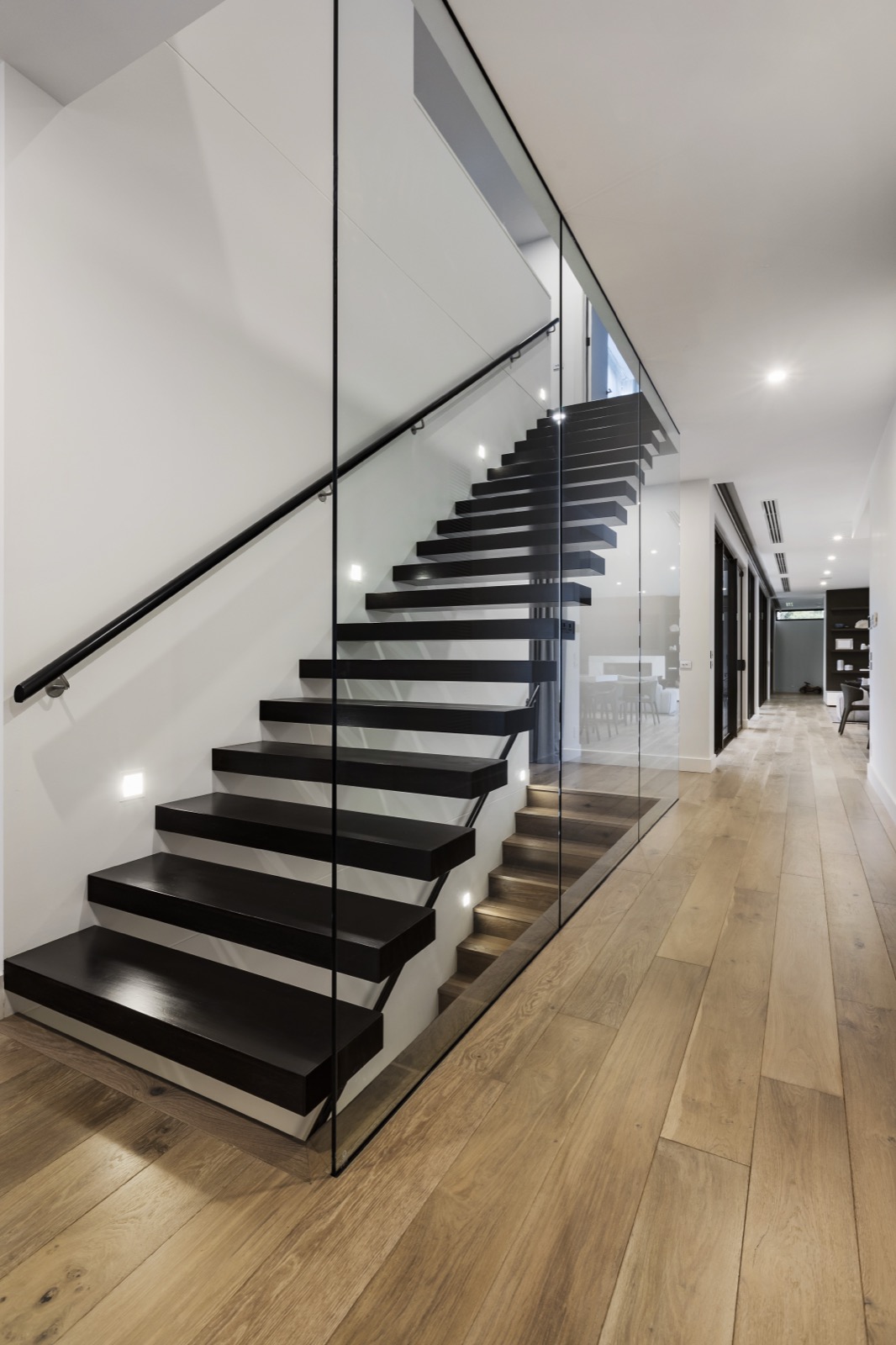 Black floating stairs with full glass wall