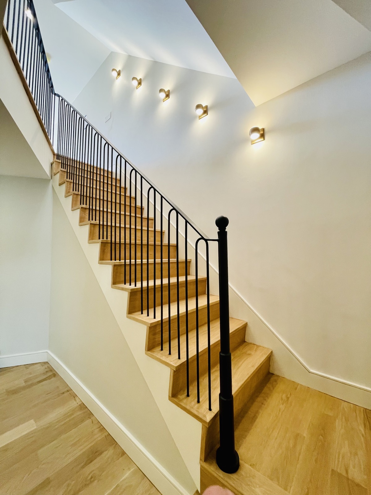 Vertical bar iron staircase with wall sconces